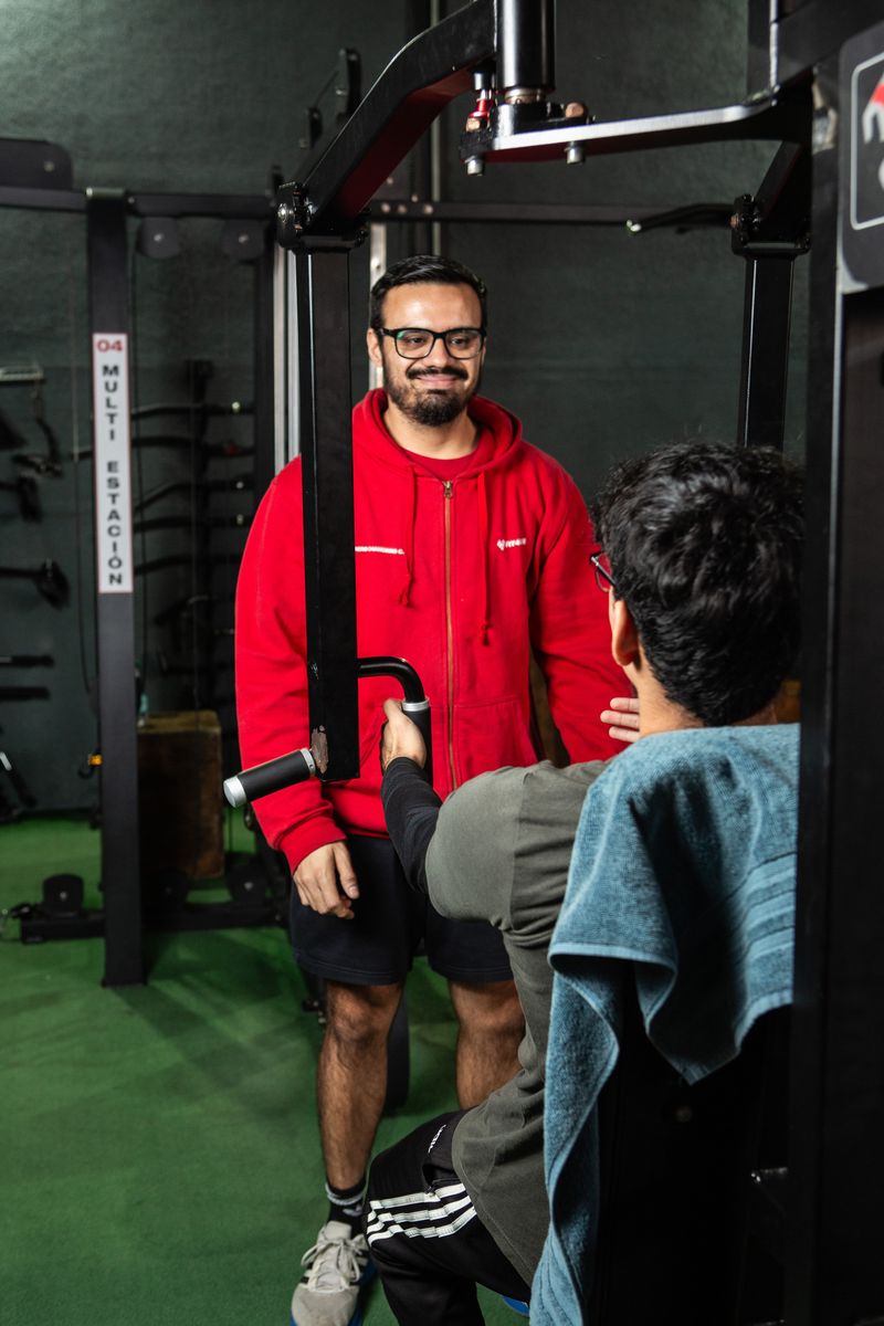 Profesional de Fit4Life sonríe junto a un alumno en el gimnasio